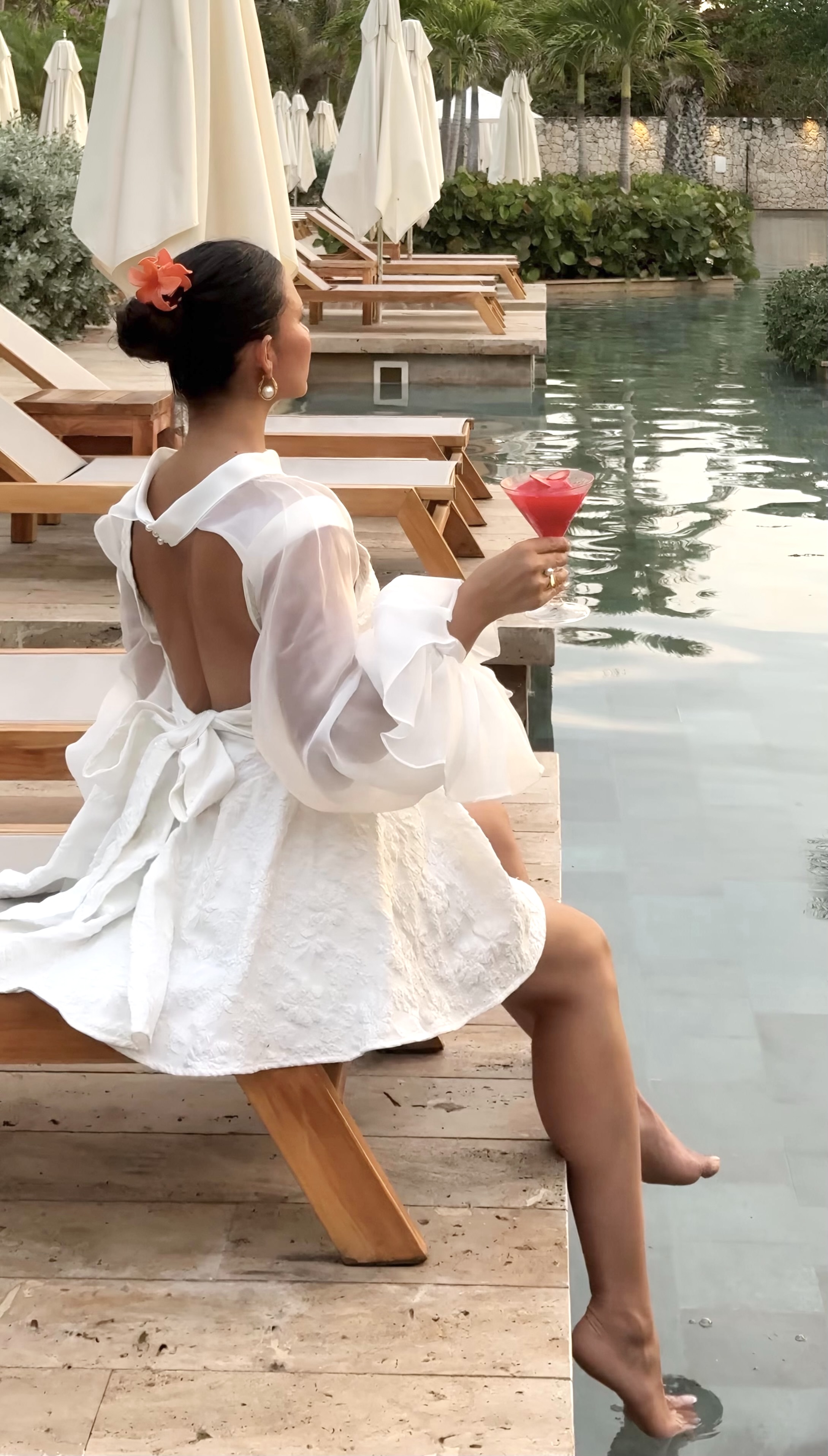 Guest sitting poolside with a red drink