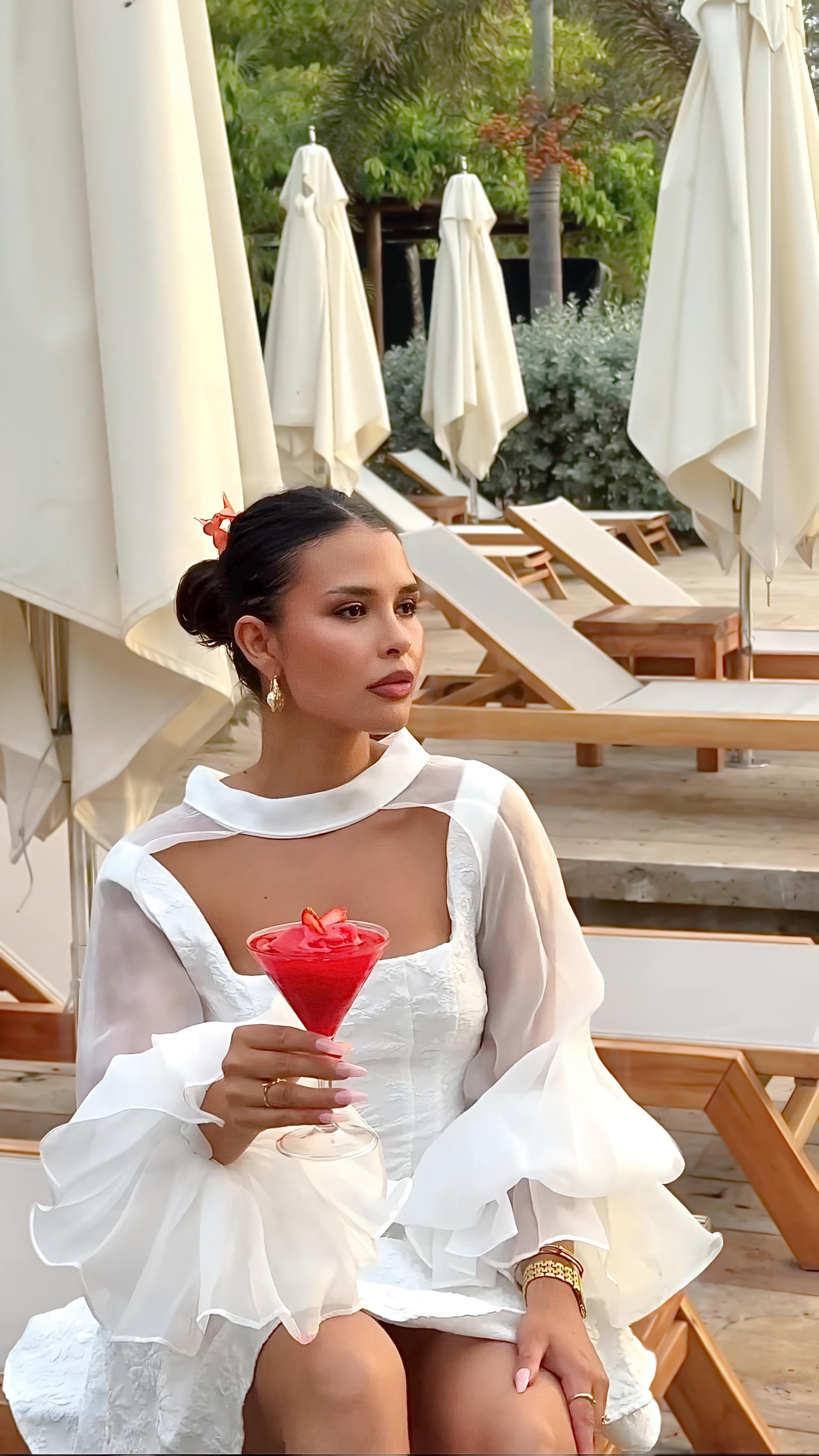 Guest in a white dress holding a red cocktail