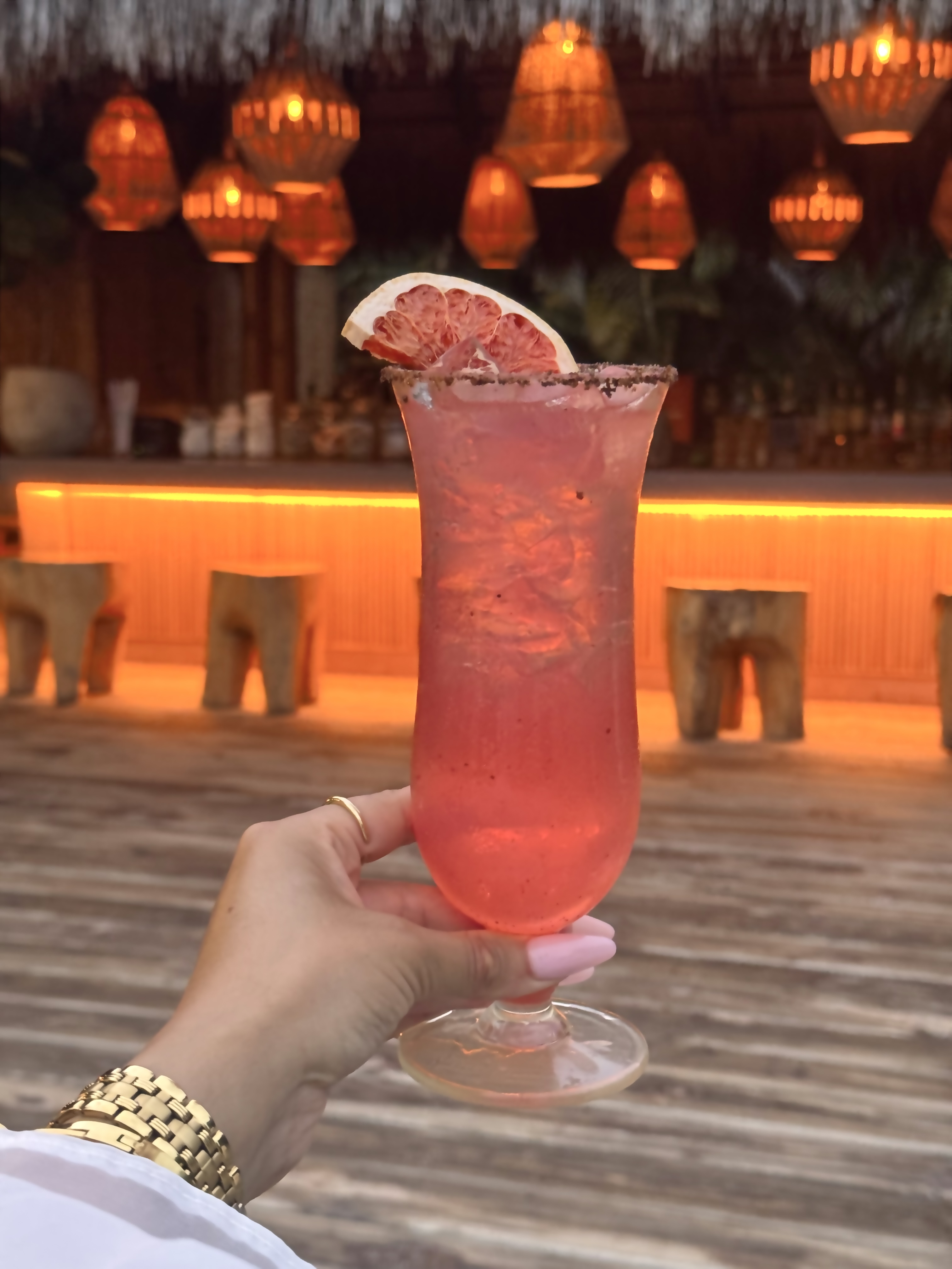 Red cocktail in front of glowing pendant lights